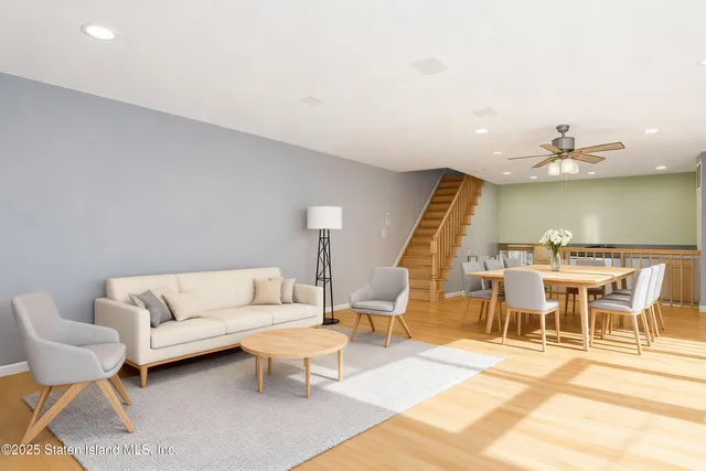 a living room with furniture a rug and a dining table with wooden floor
