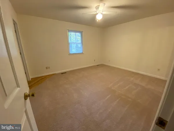 an empty room with a chandelier fan and windows