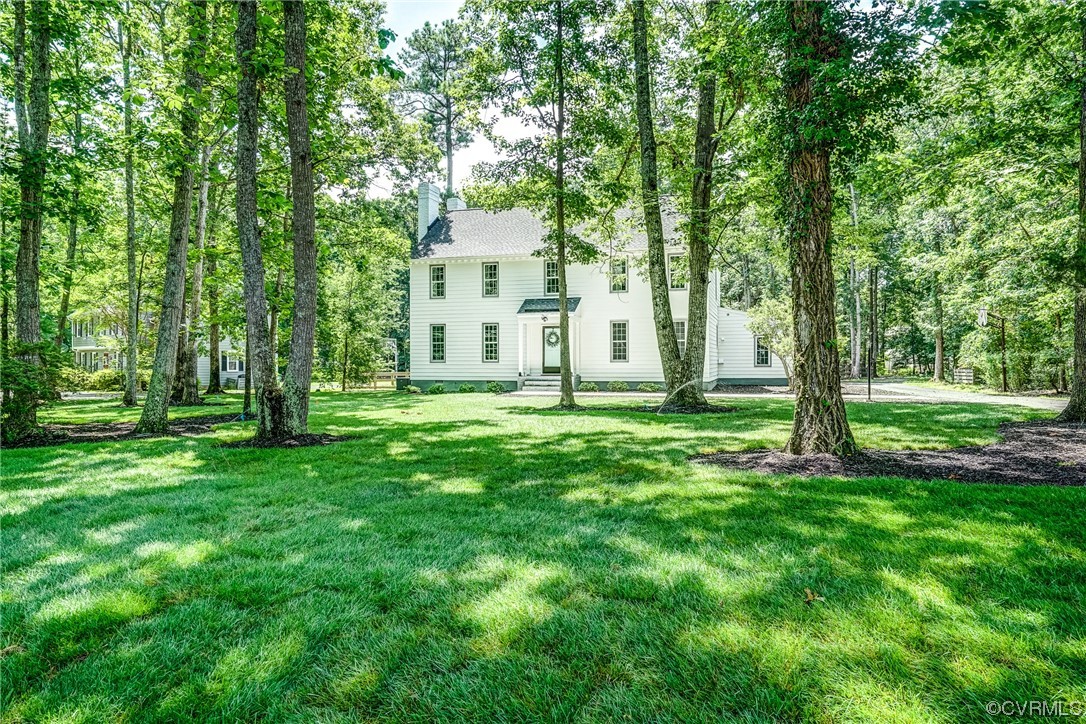 a view of a white house with a big yard and large trees