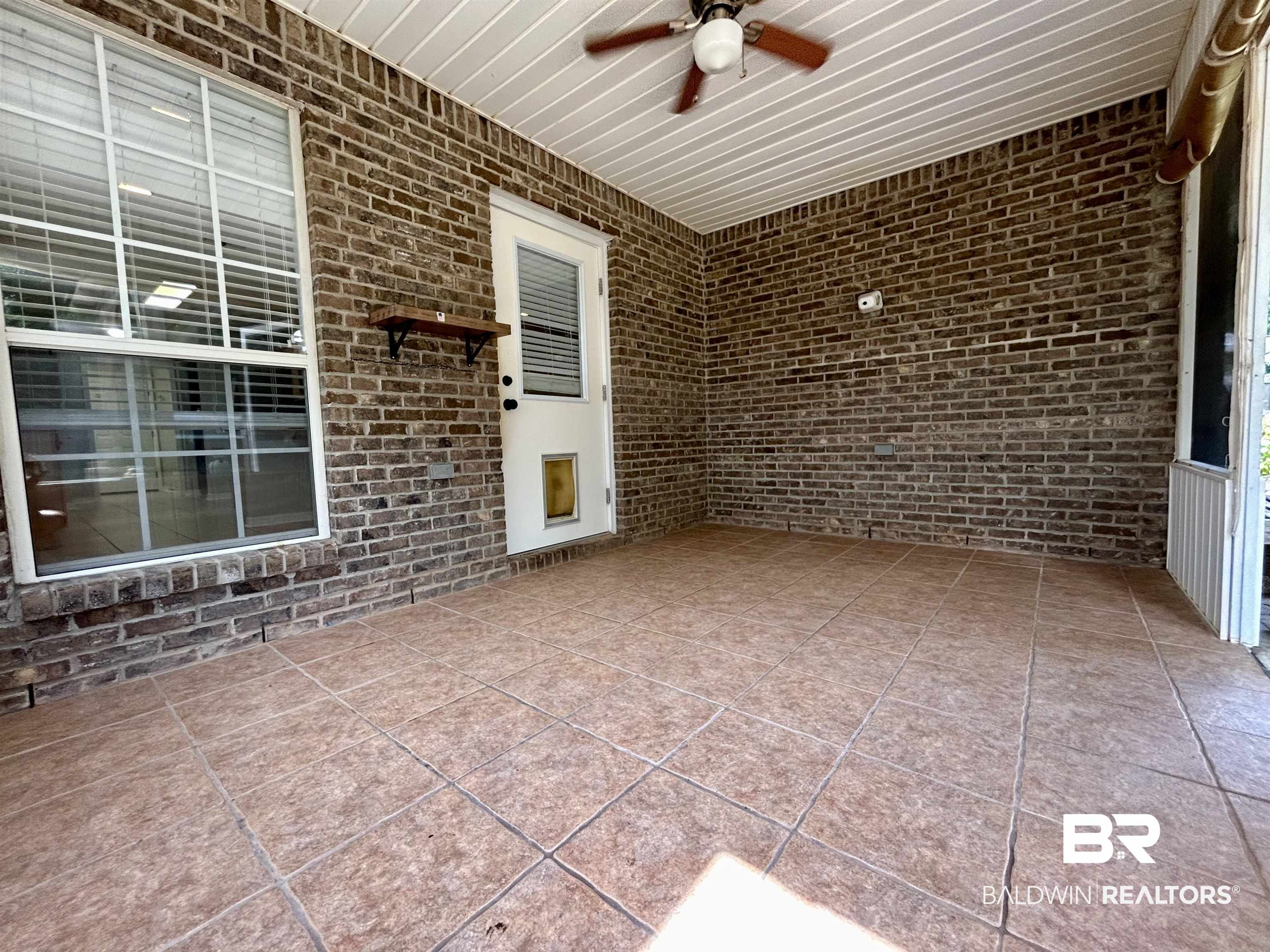 7198 Raintree Lane Gulf Shores, AL 36542 - Photo 28 of 33 Covered patio featuring brick walls, a ceiling fan, and tile flooring