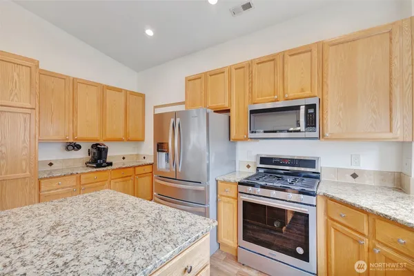 a kitchen with granite countertop a stove a sink and a refrigerator