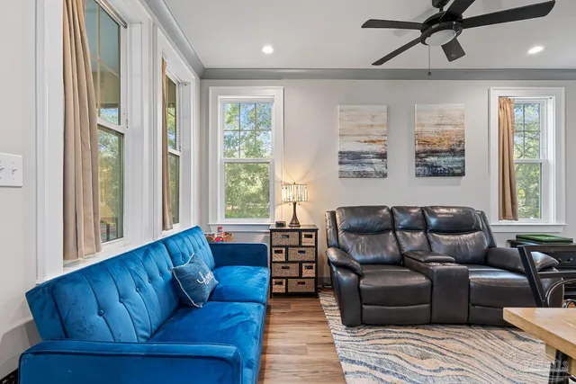 a large living room with a couch wooden floor and a large window
