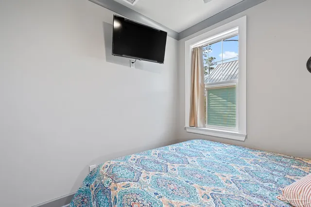 a bedroom with a bed and a flat tv screen on dresser