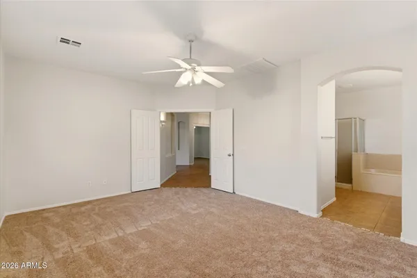 a view of an empty room with a chandelier fan
