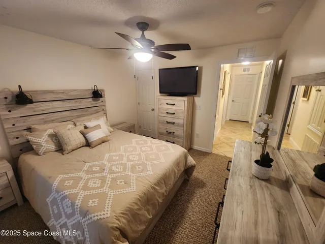 a bedroom with a bed and a flat tv screen on dresser