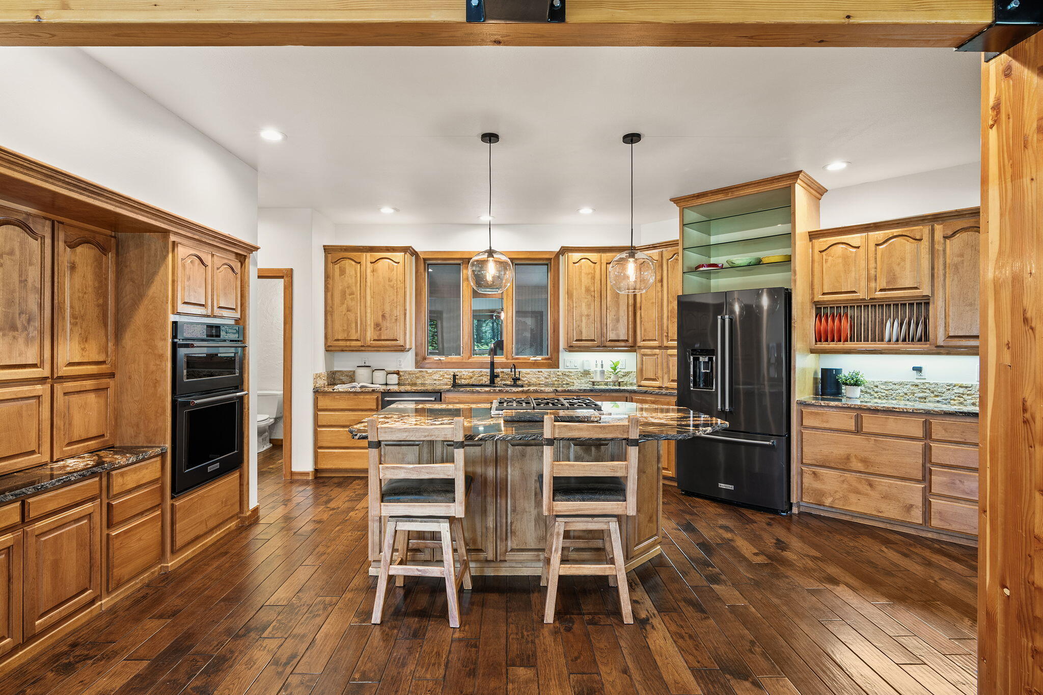 60766 Golf Village Loop Bend, OR 97702 - Photo 8 of 63 a kitchen with stainless steel appliances kitchen island granite countertop a refrigerator a stove top oven and a dining table with wooden floor