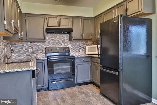 a kitchen with granite countertop stainless steel appliances and a refrigerator