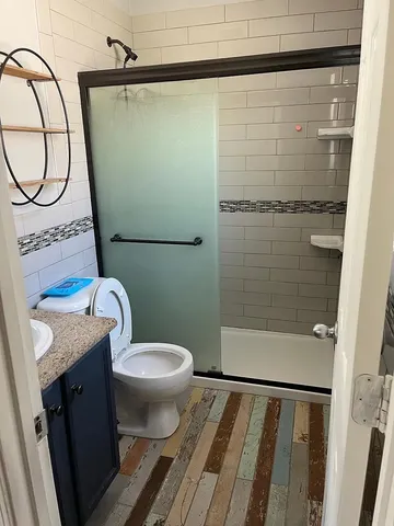 a bathroom with a granite countertop sink toilet and shower