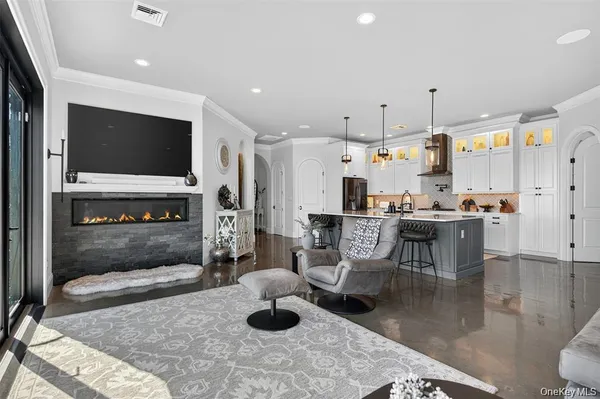 a living room with stainless steel appliances furniture a rug and a kitchen view