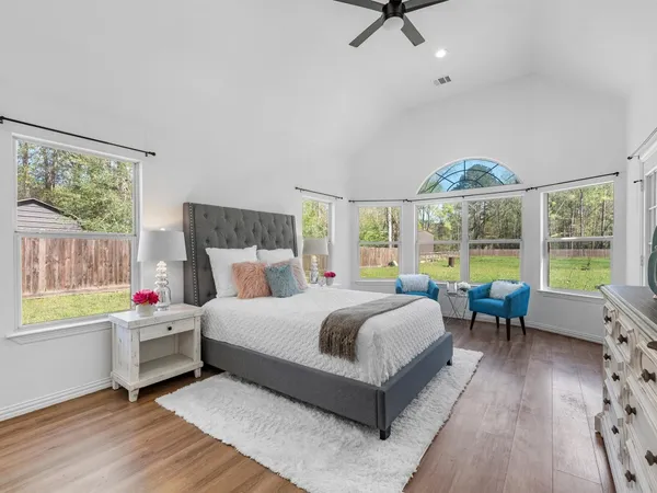 an empty room with wooden floor fan and windows
