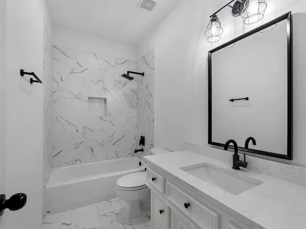 a bathroom with a toilet sink vanity granite and shower