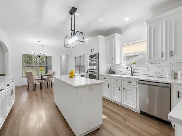 a kitchen with stainless steel appliances granite countertop a sink dishwasher a stove a dining table and chairs with wooden floor