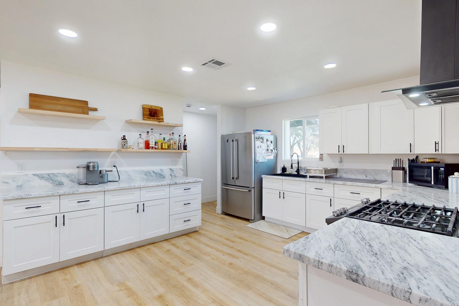 894 Grand Oroville, CA 95965 - Photo 16 of 49 a large kitchen with stainless steel appliances granite countertop a stove a sink a refrigerator and white cabinets with wooden floor