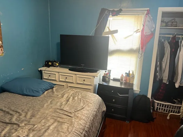 a bedroom with a bed and a flat tv screen on dresser