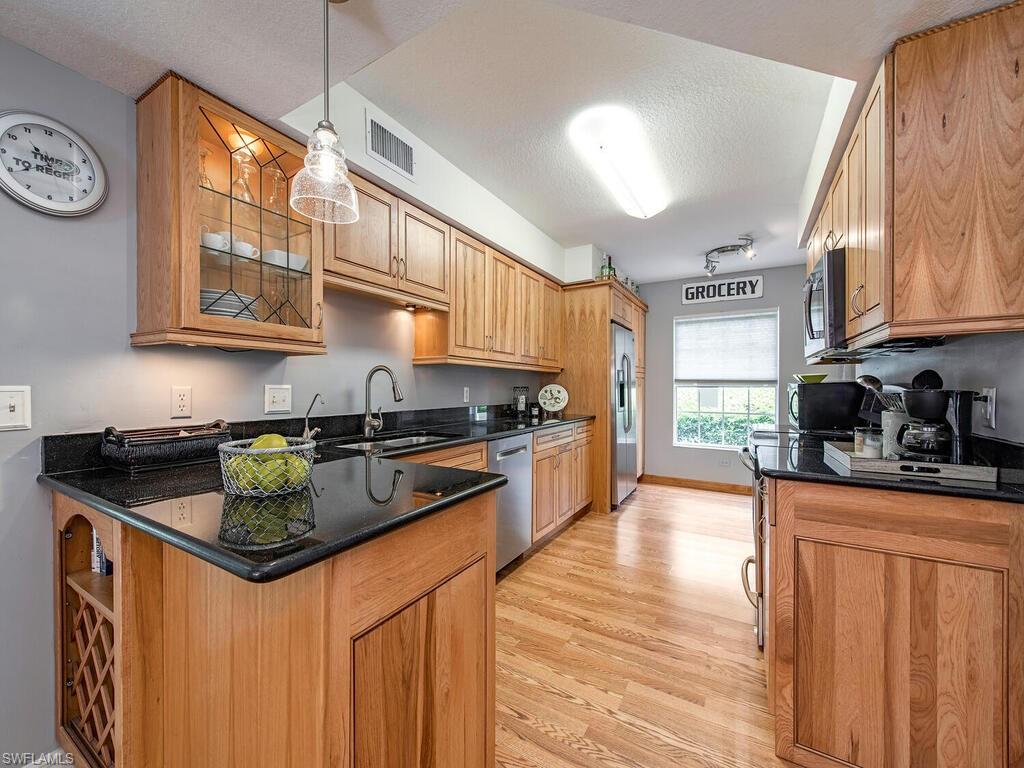 a kitchen with stainless steel appliances granite countertop a stove a sink a refrigerator and white cabinets