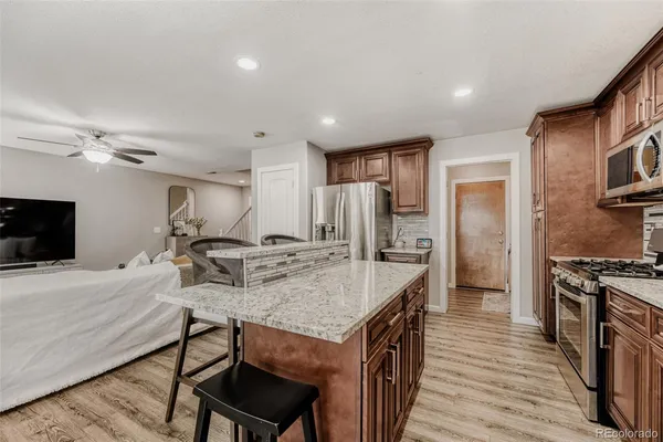 a kitchen with stainless steel appliances granite countertop a table chairs sink refrigerator and cabinets