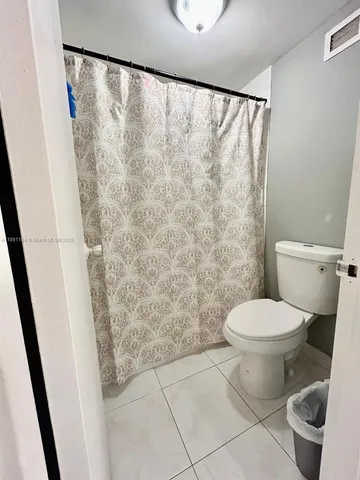 a bathroom with a toilet and a shower curtain