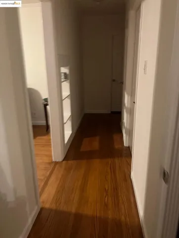 a view of a hallway with wooden floor and a living room