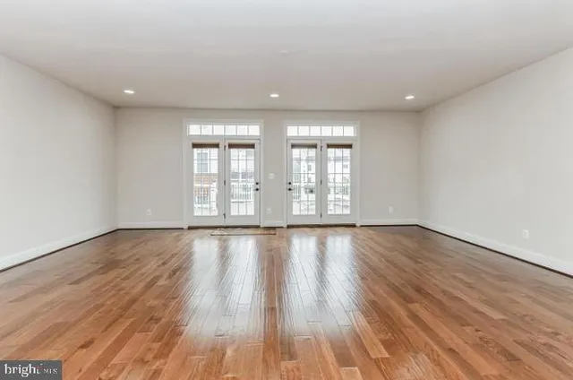 a view of an empty room with wooden floor and window