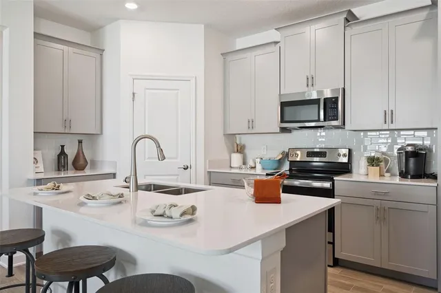 a kitchen with stainless steel appliances granite countertop a stove a sink a microwave and white cabinets