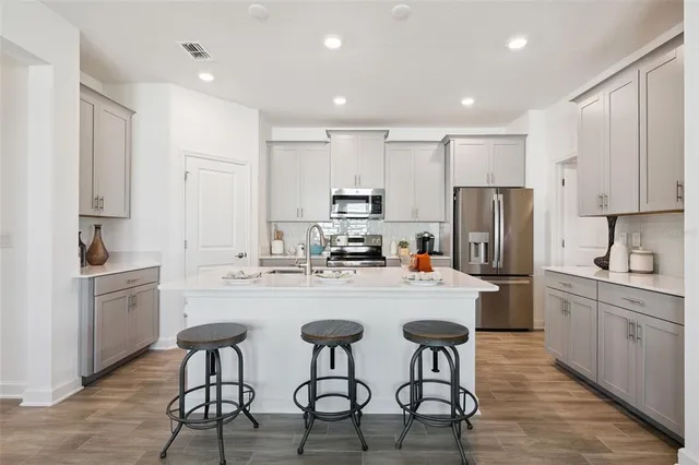 a kitchen with refrigerator a sink and chairs