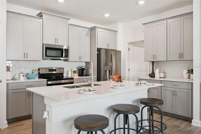 a kitchen with stainless steel appliances a stove a sink refrigerator and white cabinets