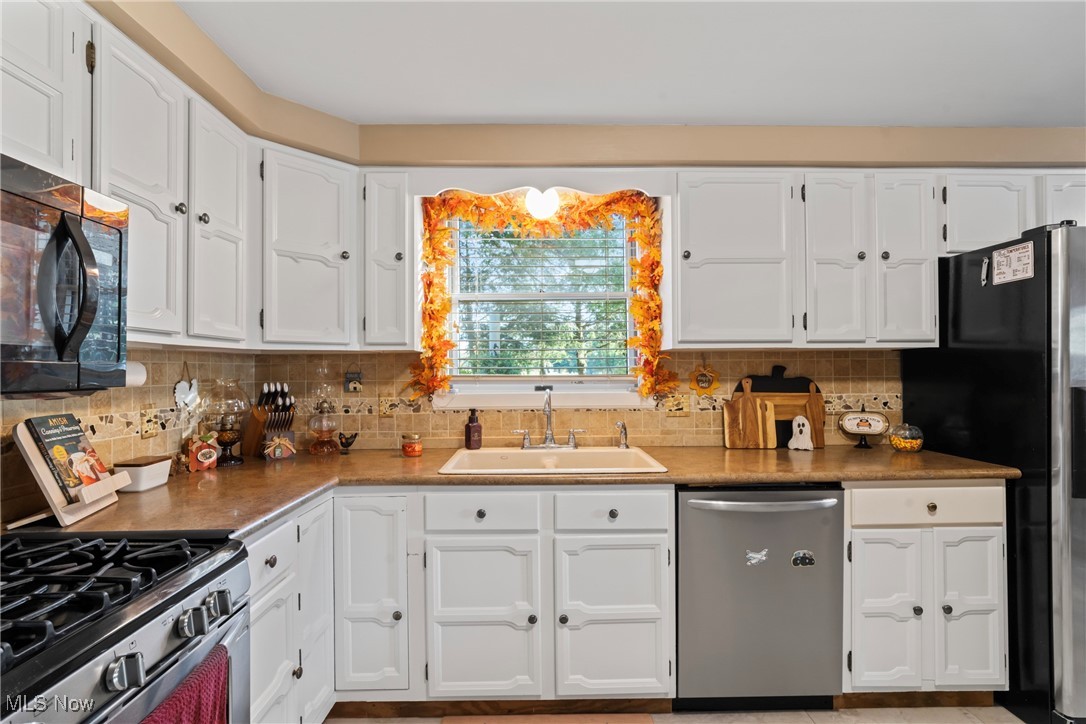3804 Ridge Road Cortland, OH 44410 - Photo 24 of 44 Kitchen featuring stainless steel appliances, white cabinets, and decorative backsplash
