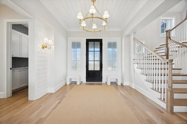 an empty room with wooden floor staircase and windows