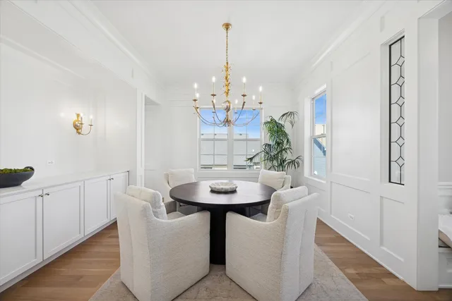a dining room with chandelier and wooden floor