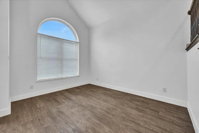 a view of empty room with wooden floor and ceiling fan
