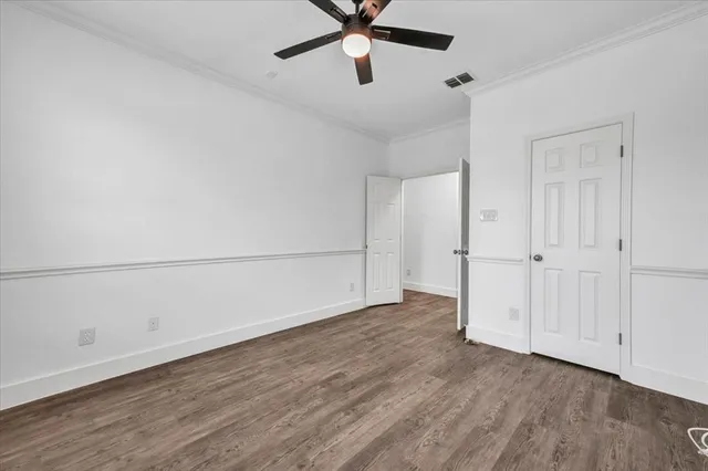 a view of a big room with wooden floor a ceiling fan and windows