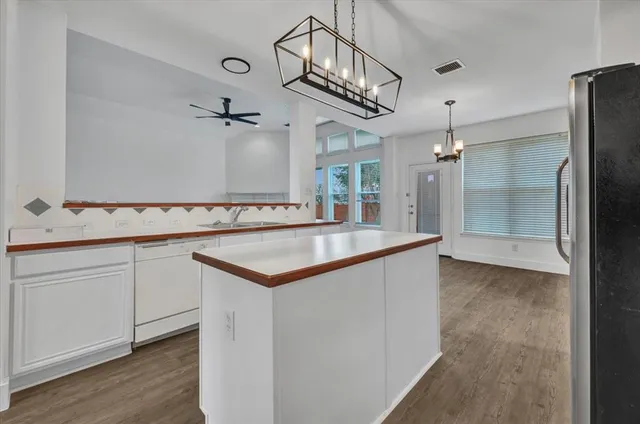 an empty room with wooden floor ceiling fan and windows