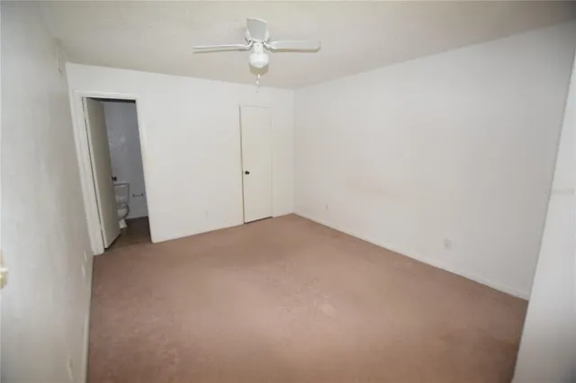 an empty room with a fan & a ceiling fan