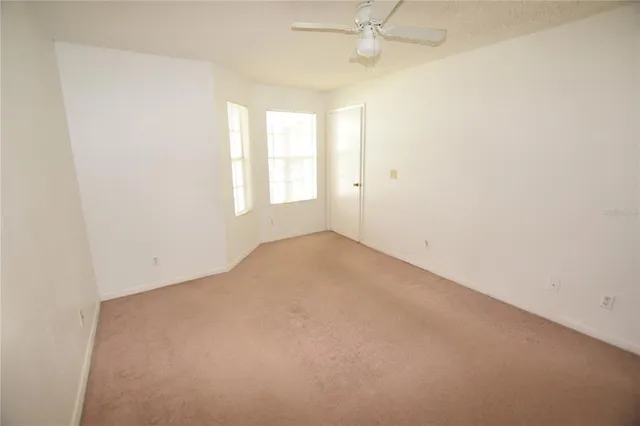 an empty room with a window and a fan