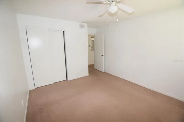 an empty room with a ceiling fan and carpet
