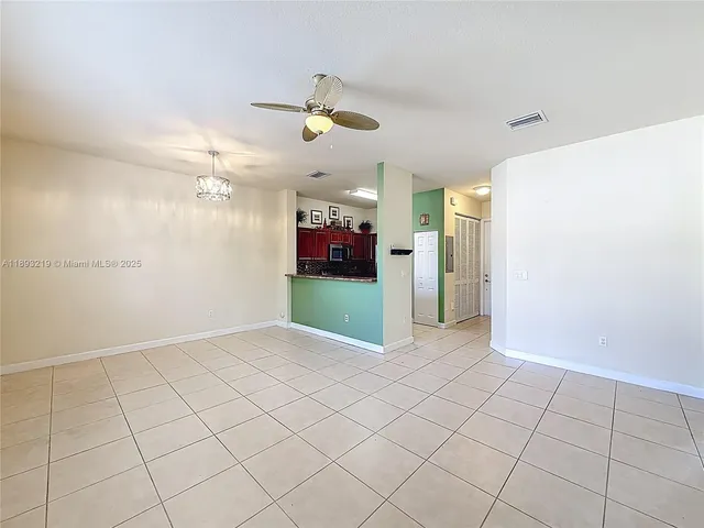 an empty room with kitchen and chandelier fan