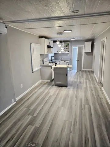 a large white kitchen with kitchen island a sink dishwasher a refrigerator and wooden floor