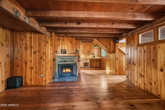 a view of an empty room with wooden floor fireplace and a window