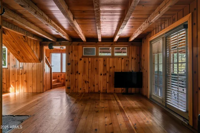a view of an empty room with wooden floor fireplace and a window