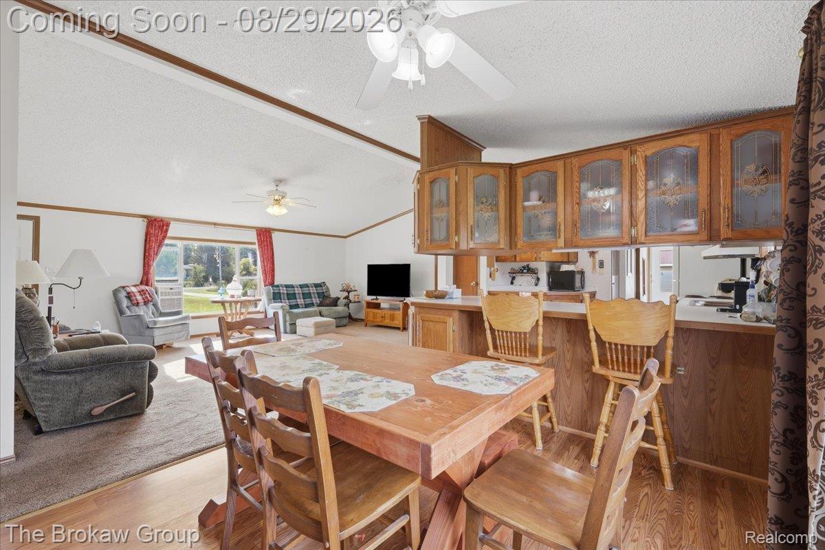 5189 North Webster Road Flushing, MI 48433 - Photo 16 of 46 Vaulted ceilings, wood-finish flooring, overhead ceiling fan, wood cabinetry with frosted glass inserts, and a functional breakfast bar