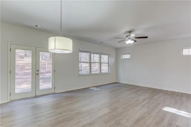 an empty room with wooden floor chandelier fan and window