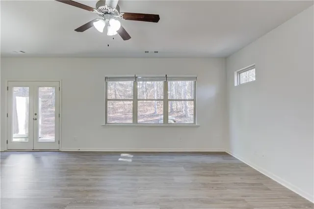 a view of an empty room with wooden floor and a window
