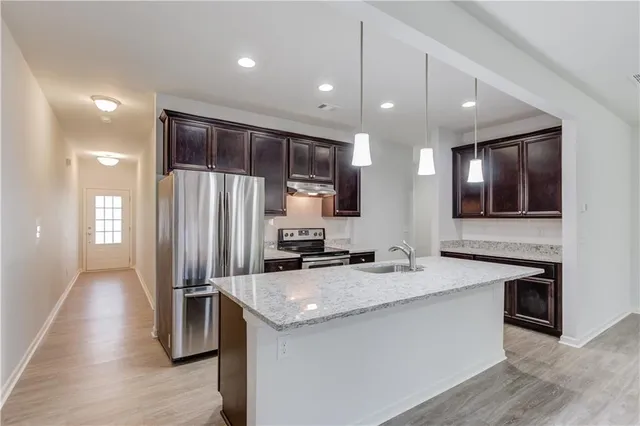 a kitchen with stainless steel appliances granite countertop a sink a stove and a refrigerator