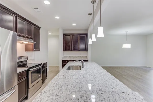 a kitchen with granite countertop stainless steel appliances and wooden floor