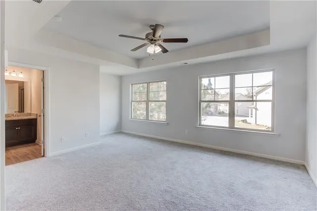 an empty room with chandelier fan and windows