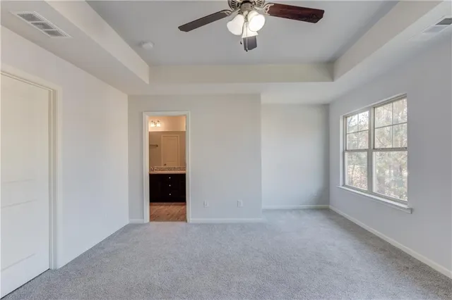 an empty room with chandelier fan and windows