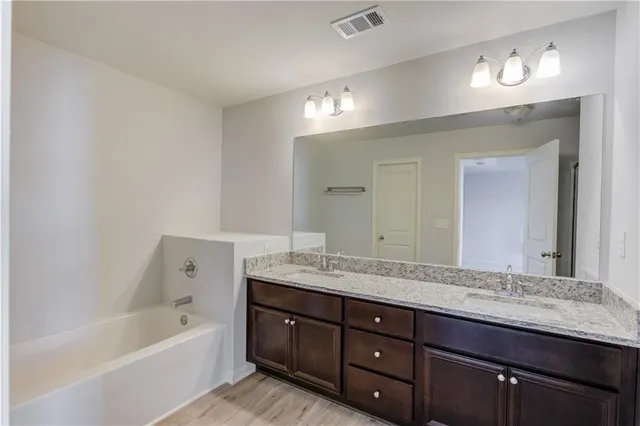 a bathroom with a granite countertop double vanity sink and a bathtub