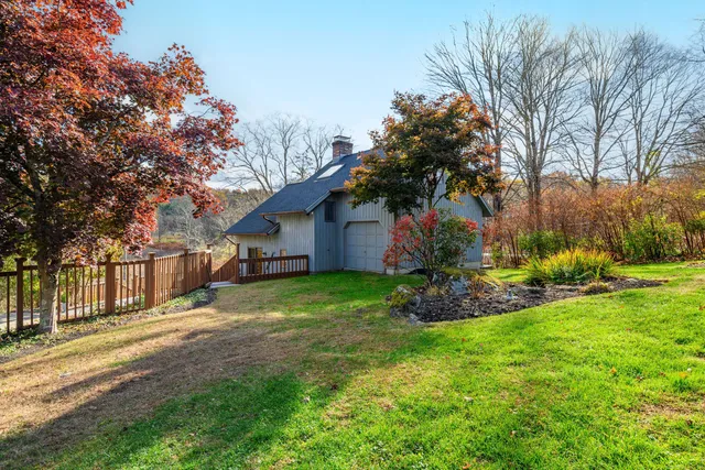 a backyard of a house with plants and large tree