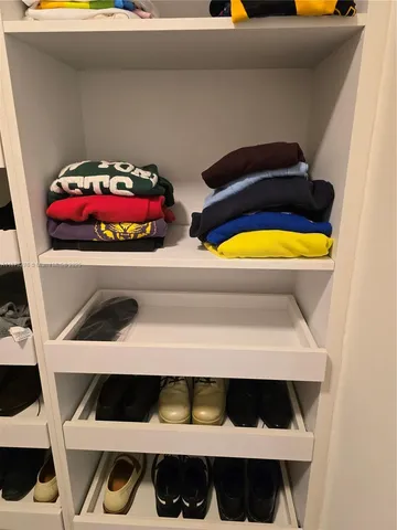 a view of walk in closet with clothes and shoes