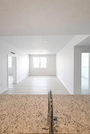 a view of a livingroom with wooden floor and kitchen space